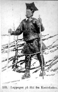 133. Mannsdrakt eller guttedrakt, Kautokeino. Portrett av mann-gutt på ski foran skigard, ant - Norsk folkemuseum - NF.06145-002