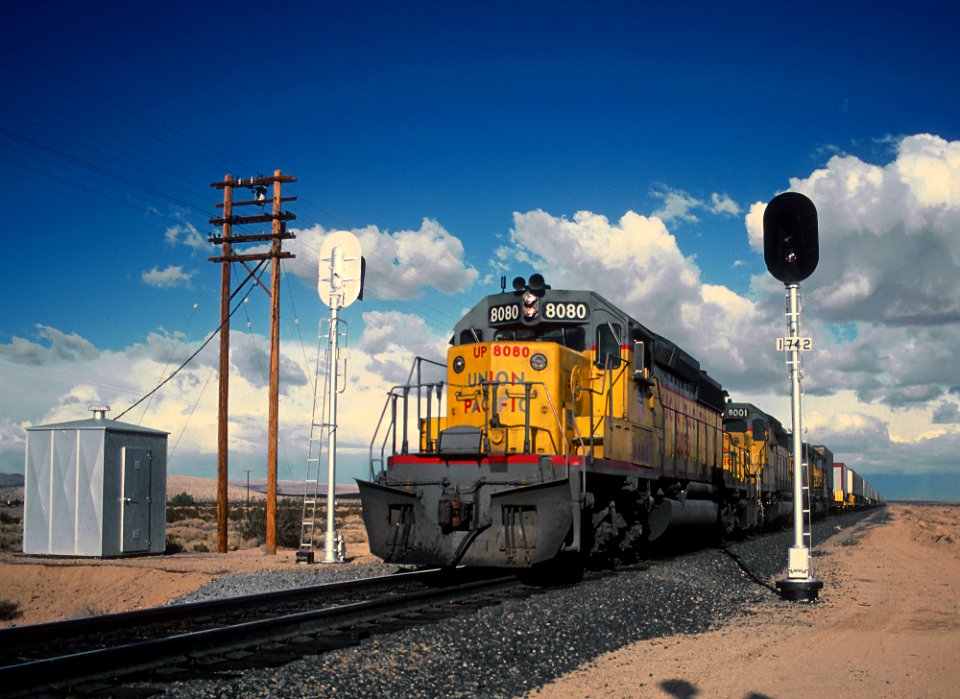 UP 8080 SD40-2H with a westbound train at Signal 1742 at the Harvard Rd. crossing about 10 mi. east of Yermo, CA in February 1981 (33133590133)