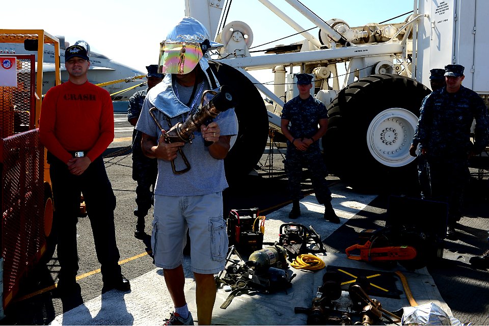 A guest touring the aircraft carrier USS Ronald Reagan (CVN 76) dons part of a firefighting ensemble 130921-N-TO979-025