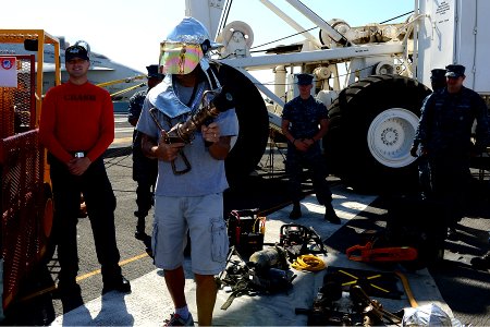 A guest touring the aircraft carrier USS Ronald Reagan (CVN 76) dons part of a firefighting ensemble 130921-N-TO979-025
