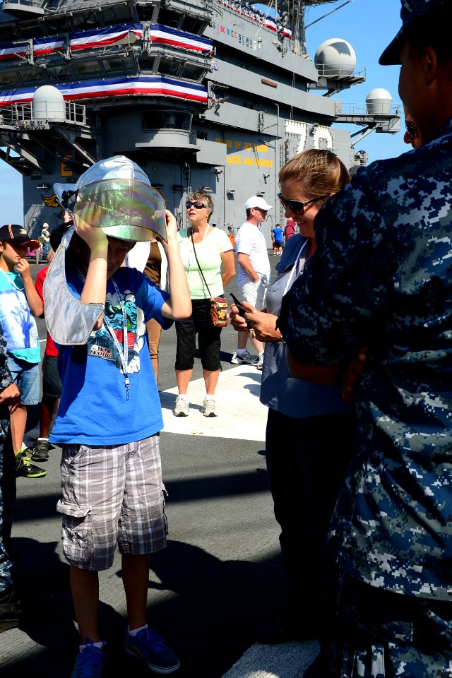 A guest touring the aircraft carrier USS Ronald Reagan (CVN 76) dons a firefighting helmet 130921-N-TO979-023