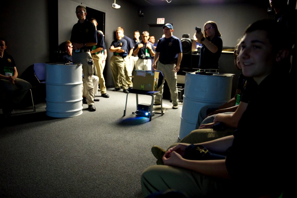 A law enforcement explorer aims her practice weapon during a drill as others watch