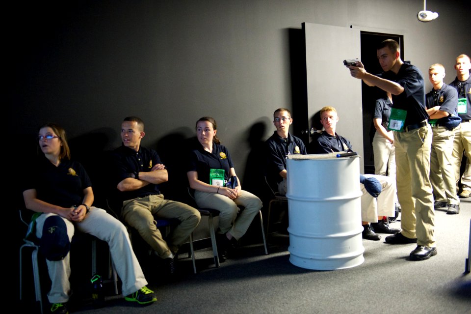 A law enforcement explorer takes aim with a practice weapon while others look on