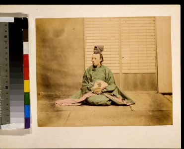 A man, possibly a government official, holding a fan, seated, facing left, wearing a crown-like hat LCCN2009632880