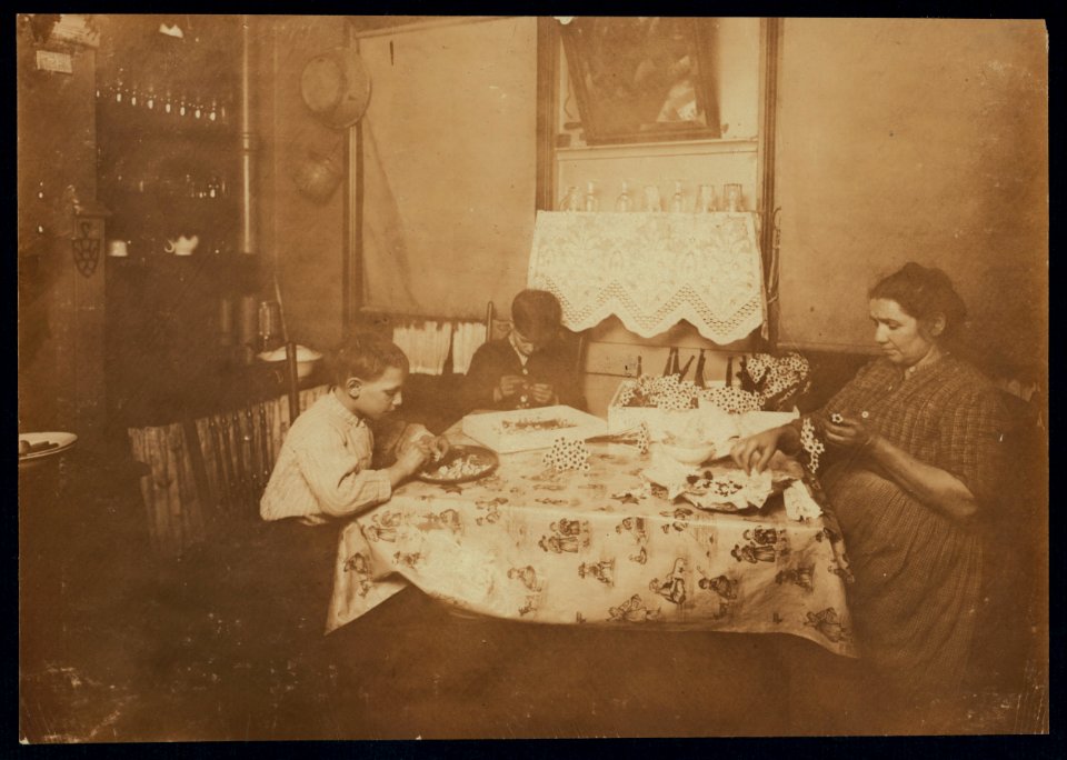 A Night Scene (Photo by 9-00 P.M.) Flower making. Family of Mary Bezzola, 212 Sullivan St., N.Y. George (10 years old) and Levia (9 years old) work until 9-00 P.M. when work is rushing. LOC nclc.04141