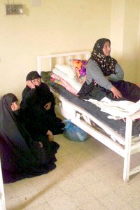 A patient at the Karbala City Women Hospital, in Karbala, Iraq, sits up on an outdated hospital bed while family members sit on the floor. DM-SD-04-04692