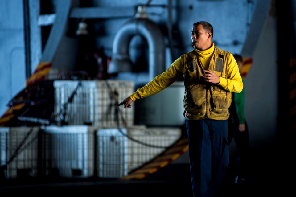 A Sailor directs aircraft in a hangar bay at sea. (8181936913)