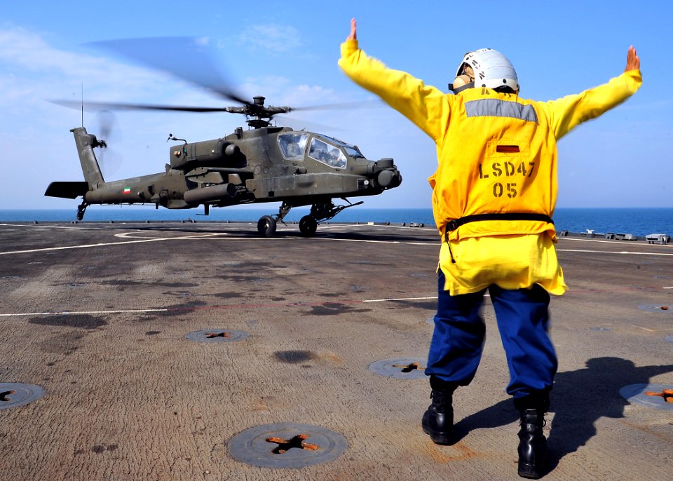 A Sailor directs an AH-64D aboard USS Rushmore. (8247724756)