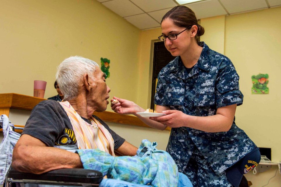 A Sailor feeds a patient at St. Dominic’s Senior Care Center. (16927319772)