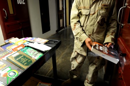 A sailor from detainee programs distributes a book from the detainee library in Camp Five DVIDS364396