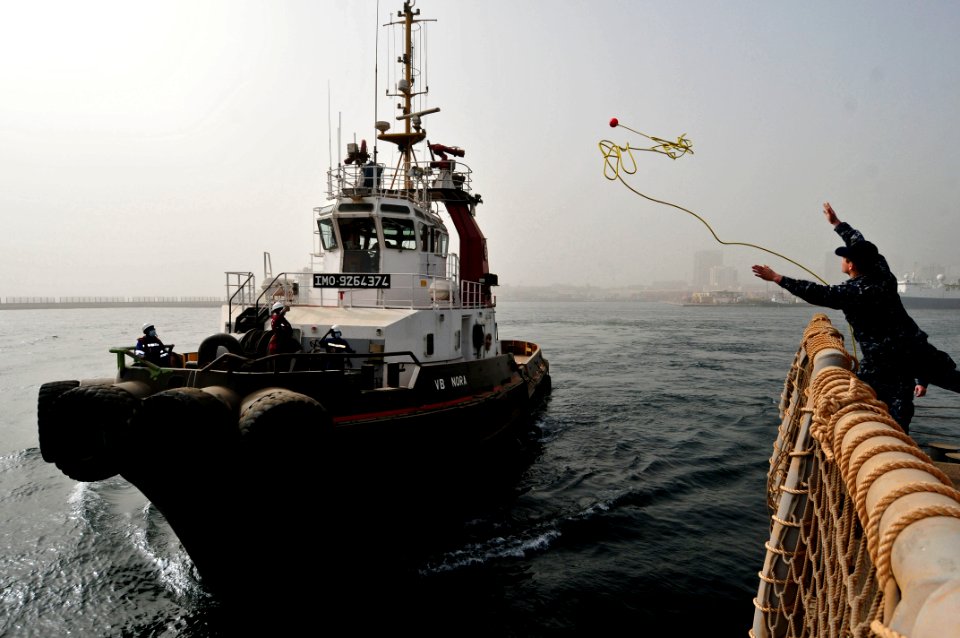 A Sailor heaves a mooring line to a tugboat. (6846520023)