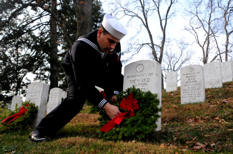 A Sailor places a holiday wreath on a grave at Arlington National Cemetery. (15842892160)