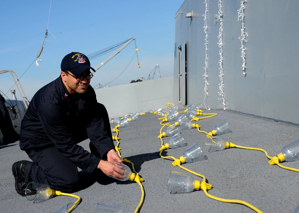 A Sailor sets up lights aboard PCU Anchorage. (8246658947)
