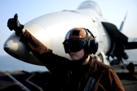 A Sailor signals to move an F-A-18C at sea. (8426059557)