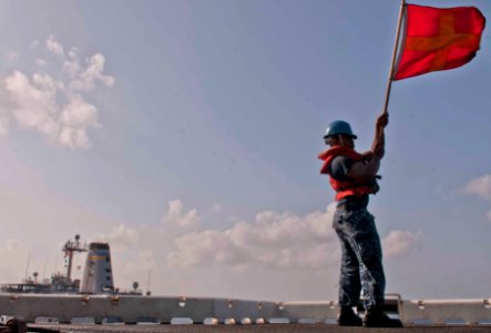 A Sailor waves the Romeo flag during a replenishment-at-sea. (8592537722)