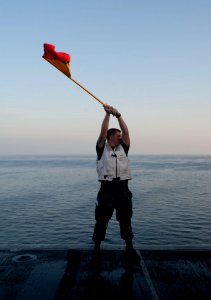 A Sailor waves a flag during a replenishment-at-sea. (8200231924)