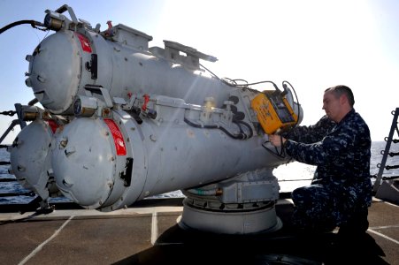A Sailor works on a torpedo tube at sea. (8498335738)