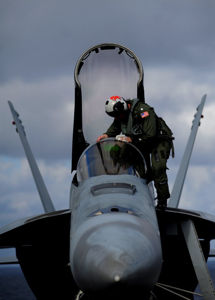 A sailor wipes down the windshield of an F A-18E Super Hornet. (8744190969)
