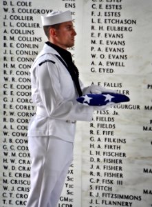 A Sailor stands with a flag at the USS Arizona Memorial. (8264508522)