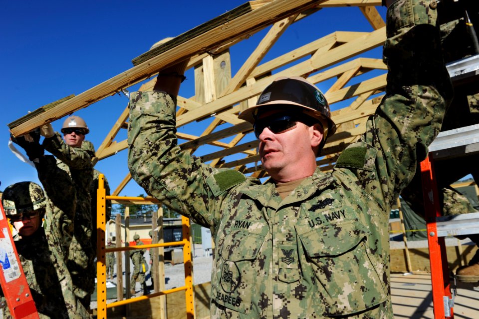 A Seabee holds up an A-frame as a hut is taken down. (8516135634)