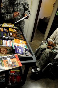 A soldier from the detainee library reviews a book record before offering books to a detainee in Camp Five DVIDS368271