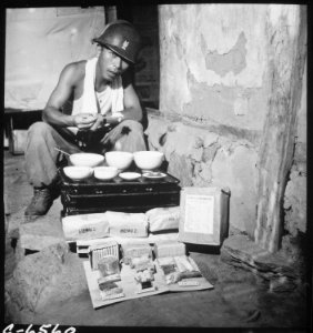 A soldier of the Republic of Korea Army eating lunch in a war-destroyed house in Munsan-ni, Korea, as a field ration... - NARA - 530635
