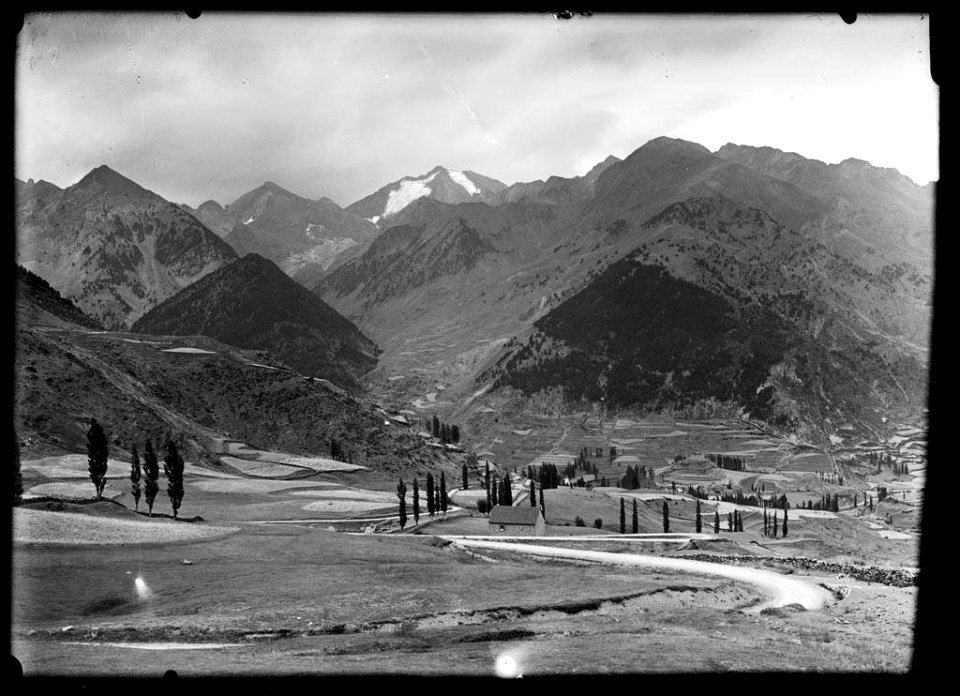 Alguns edificis i conreus a la vall de Sallent de Gállego i al fons els pics de los Infiernos