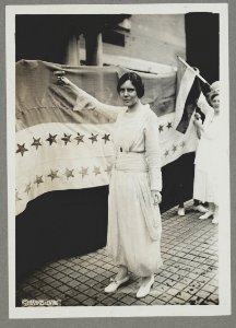 Alice Paul, full-length portrait, standing, facing left, raising glass with right hand LCCN97500088