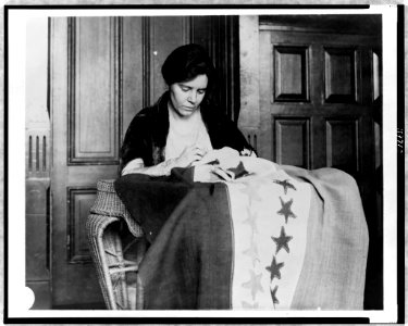 Alice Paul, half-length portrait, seated, facing slightly right, sewing suffrage flag LCCN97519946 photo