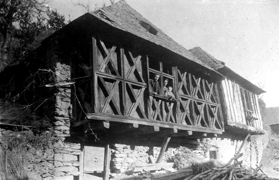 Balconada de fusta de Casa Toquera amb família a la finestra