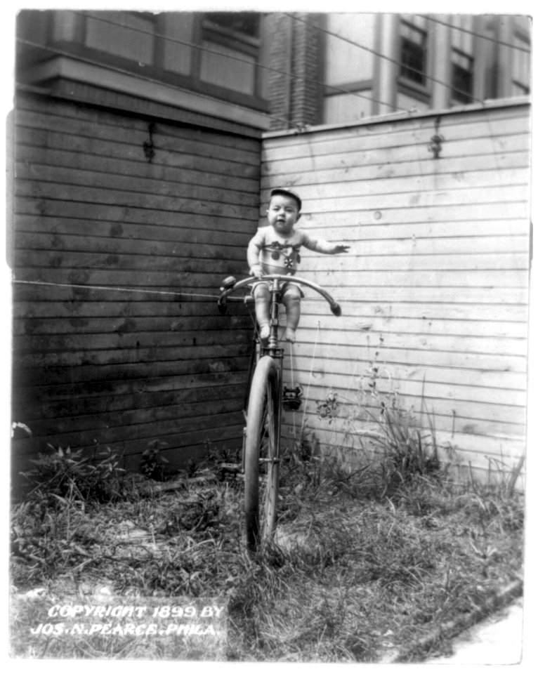 Baby on large unicycle held up by ropes LCCN2002724034