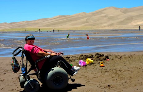 Woman in Dunes Wheelchair Beside Medano Creek (31766013238) photo