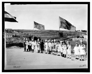 American Colony children in Fourth of July pageant, Jerusalem, showing boys lined up holding toy rifles and Anna Grace and Tanetta Vester holding flags LCCN2008676308