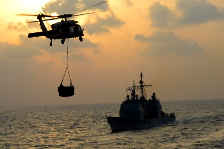 An MH-60S carries cargo past USS Mobile Bay (8364955876)