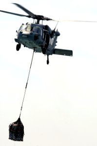 An MH-60S Seahawk helicopter assigned to Helicopter Sea Combat Squadron (HSC) 23 carries supplies from the fast combat support ship USNS Bridge (T-AOE 10) to the amphibious dock landing ship USS Comstock (LSD 110517-N-RC734-113