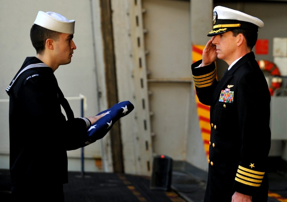 An officer salutes a flag during a burial at sea. (8202184203)