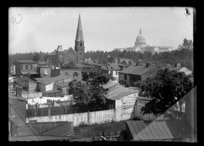 An overview of Wesley Zion Church in the midst of public housing, old wooden structures and trees; United States Capitol building on far right LCCN2016647091
