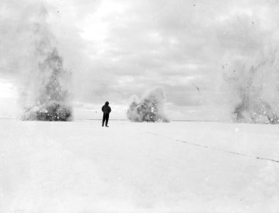 An unidentified man standing with his back to a simultaneous triple explosion RMG P49447
