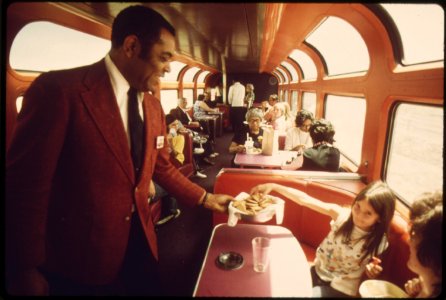 An-amtrak-passenger-service-director-serves-cookies-to-passengers-in-the-lounge-car-of-the-southwest-limited-enroute-from-albuquerque-new-mexico-to-dodge-city-kansas-june-1974 7158197948 o photo