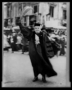 Anna Howard Shaw, full-length portrait, standing, facing front, wearing academic robe and holding large feather LCCN97500089