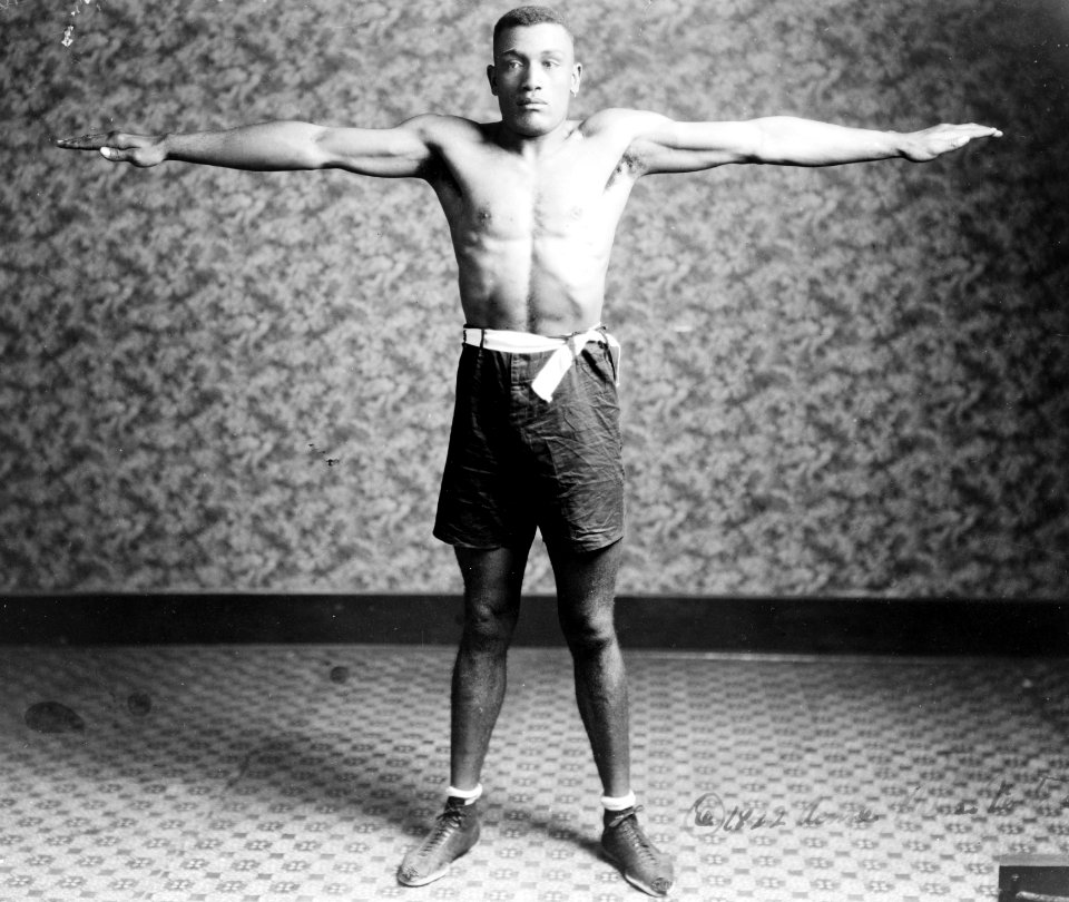 Boxer Tut Jackson clothed in boxing trunks, full-length portrait, standing, facing front, with his arms extended out from his sides, showing his reach LCCN92511772 (cropped)