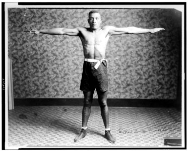 Boxer Tut Jackson clothed in boxing trunks, full-length portrait, standing, facing front, with his arms extended out from his sides, showing his reach LCCN92511772