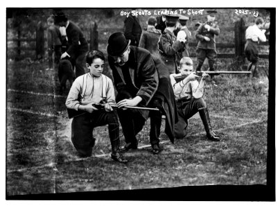 Boy Scouts learning to shoot. Two boys kneeling on ground with the instuctor between. LCCN2014688125 photo