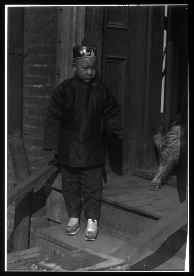 Boy standing on steps in front of a doorway, Chinatown, San Francisco LOC agc.7a55054