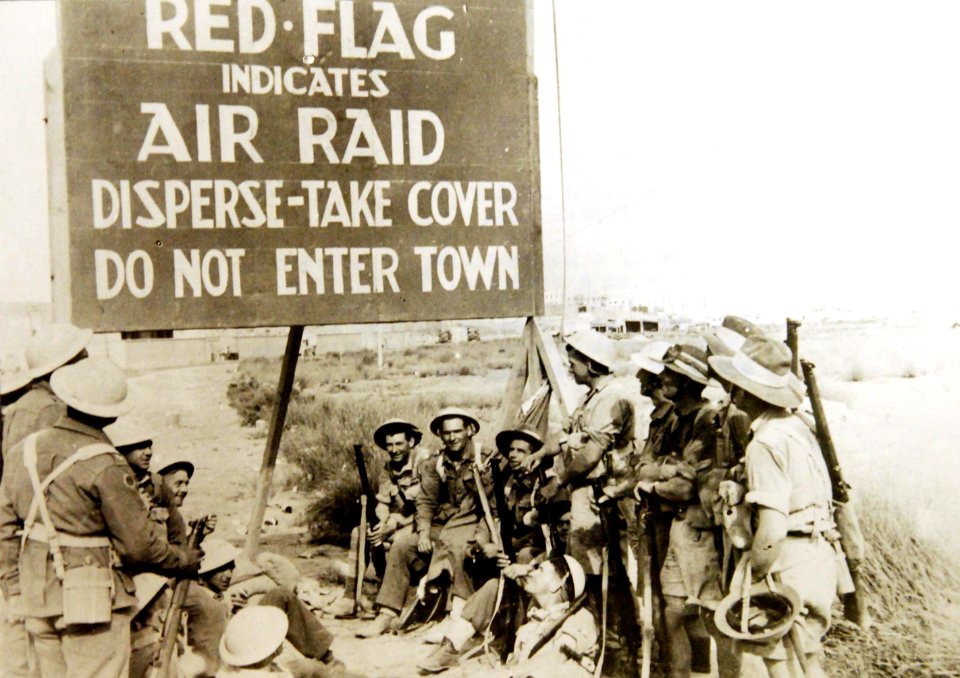 British members of a motor-transport pause at a notice on a road near Tobruk, Libya, WWII (37101819091)