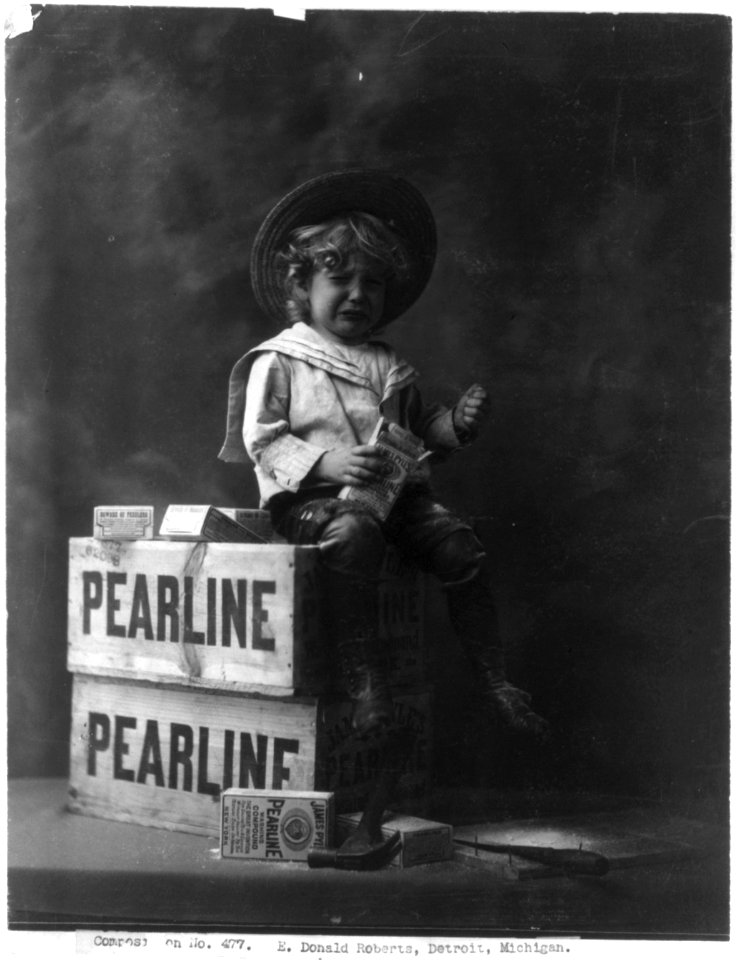 Child seated on crate, holding box of Pearline washing compound, and crying LCCN2003654924