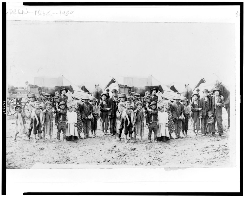 Children posed in front of horse-drawn wagons and tents LCCN95507108