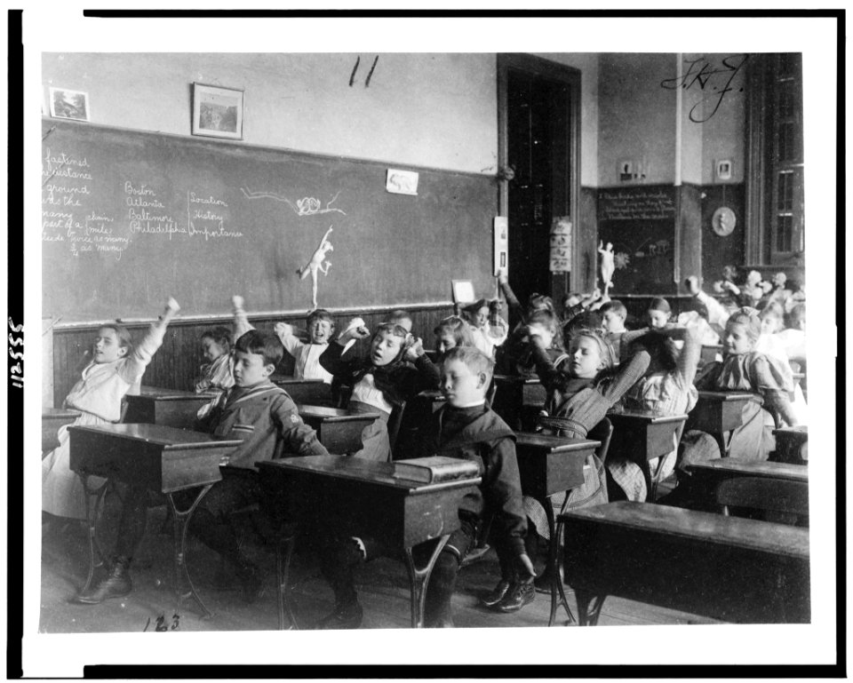 Children seated at desks in Washington, D.C. classroom, stretching LCCN95500447