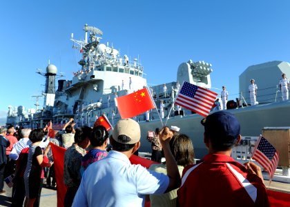 Chinese citizens wave the U.S. and China flags as the Liberation Army-Navy ship Qingdao (DDG 113) arrives in Hawaii for a scheduled port visit