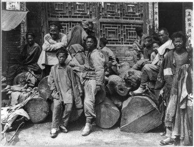 Chinese men and boys on street around pile of logs LCCN2006675661
